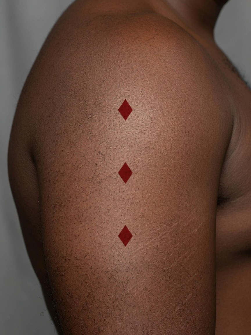 3 of Diamonds pip tattoo on the upper arm