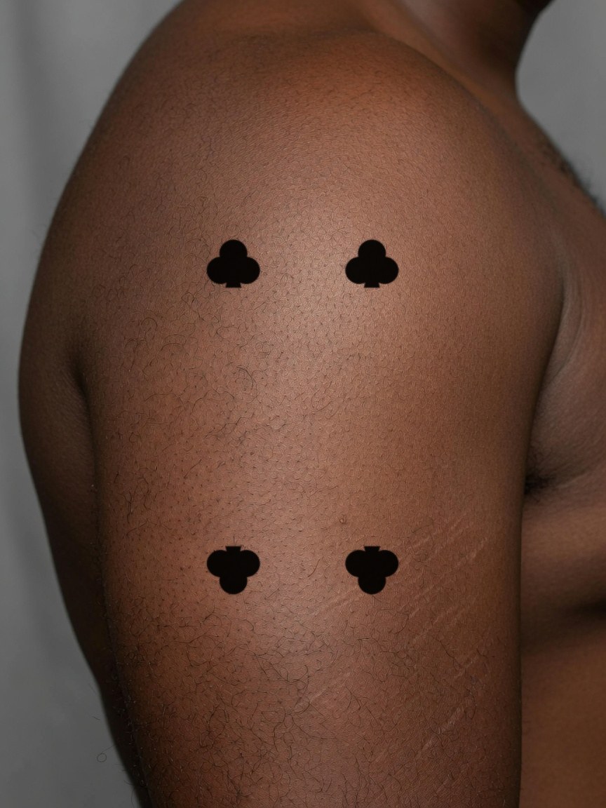 4 of Clubs pip tattoo on the upper arm