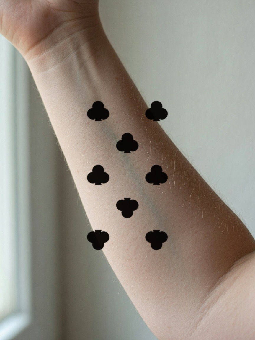 8 of Clubs pip tattoo on the inner forearm