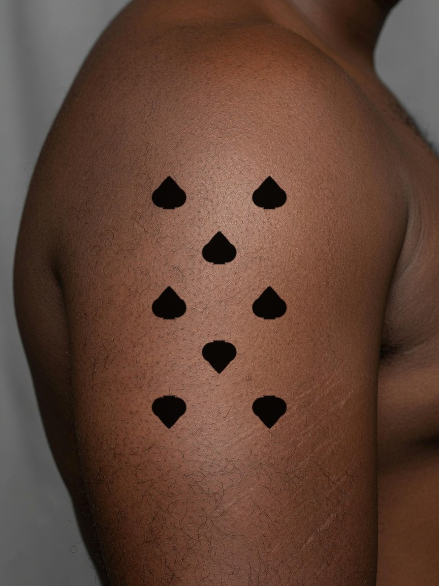 8 of Spades pip tattoo on the upper arm